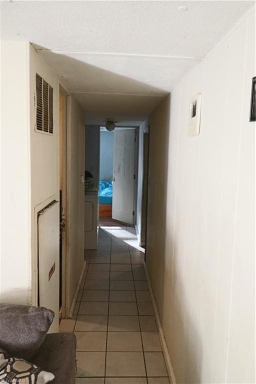 hall with washer / dryer and dark tile patterned flooring