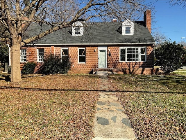 cape cod-style house featuring entry steps, a front yard, brick siding, and a chimney