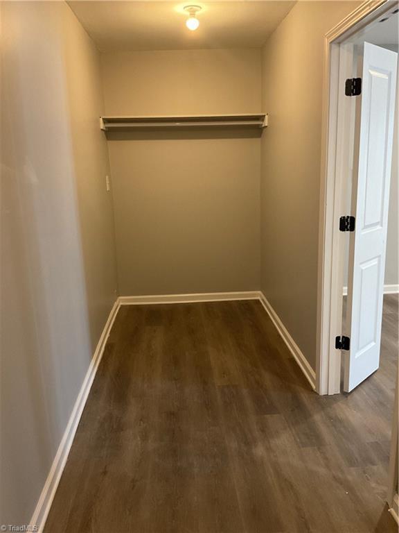 walk in closet with dark hardwood / wood-style flooring