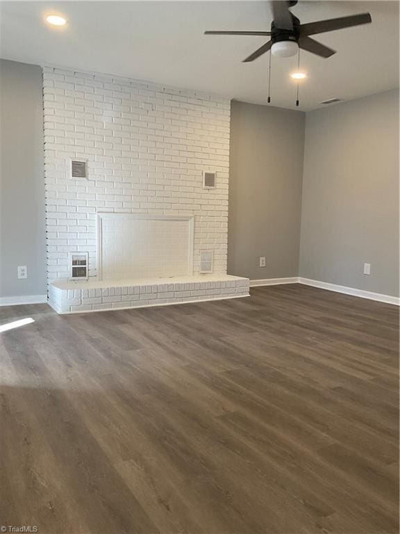 unfurnished living room with ceiling fan, dark hardwood / wood-style flooring, and a brick fireplace