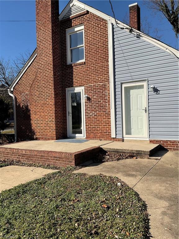 back of property with brick siding, a chimney, and a patio area