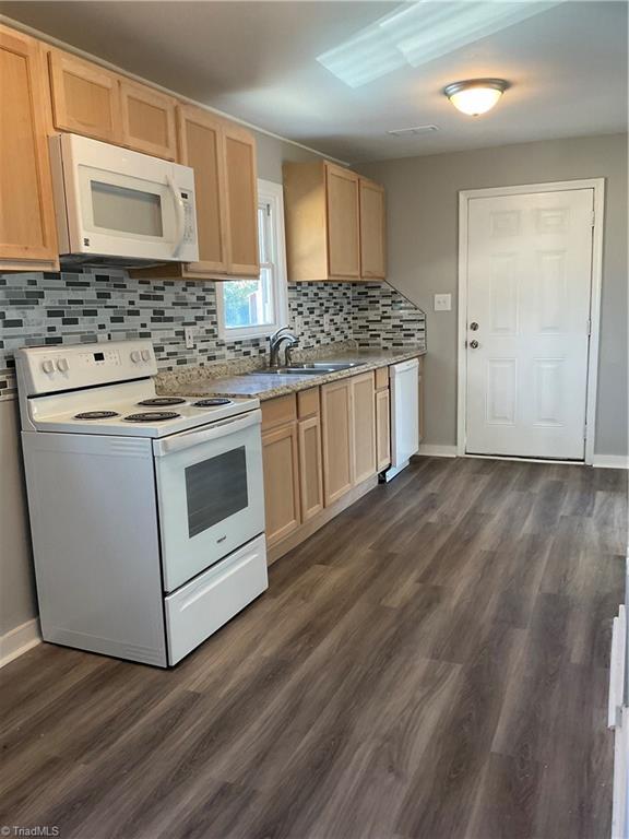 kitchen with light brown cabinetry, white appliances, dark wood-type flooring, and sink