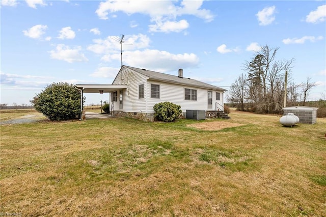 back of house with central AC unit, a lawn, and a carport