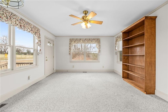 empty room with ceiling fan, a wealth of natural light, ornamental molding, and light carpet