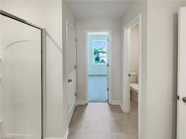 full bathroom with toilet, a stall shower, and baseboards