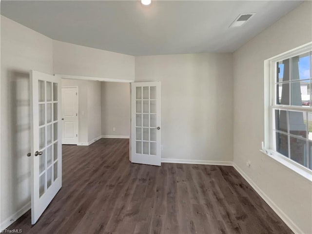 empty room featuring dark wood-type flooring, french doors, visible vents, and baseboards