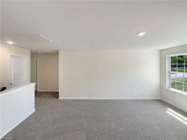 unfurnished room featuring attic access, carpet flooring, and baseboards