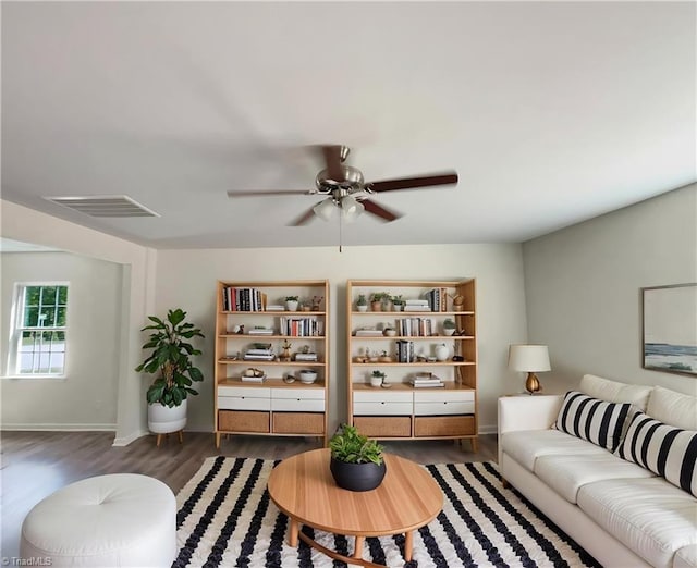 living area with baseboards, visible vents, wood finished floors, and ceiling fan