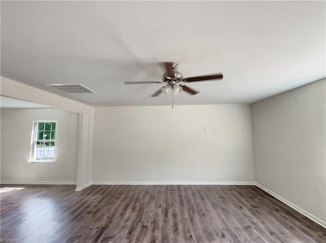 spare room with wood finished floors, a ceiling fan, visible vents, and baseboards