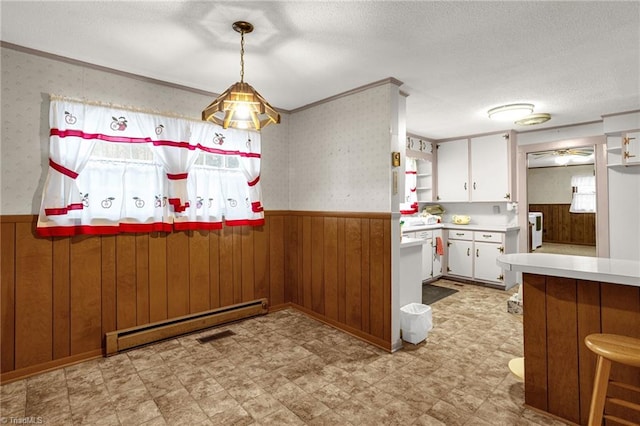 kitchen with pendant lighting, wooden walls, white cabinetry, baseboard heating, and kitchen peninsula