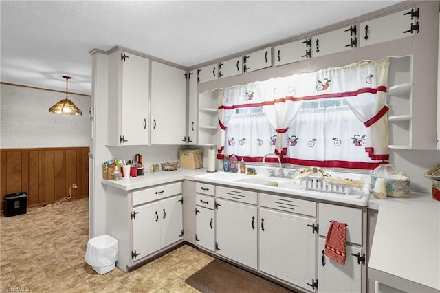 kitchen featuring hanging light fixtures, white cabinetry, and wooden walls