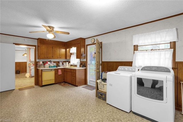 clothes washing area with ceiling fan, wooden walls, washing machine and dryer, and a textured ceiling