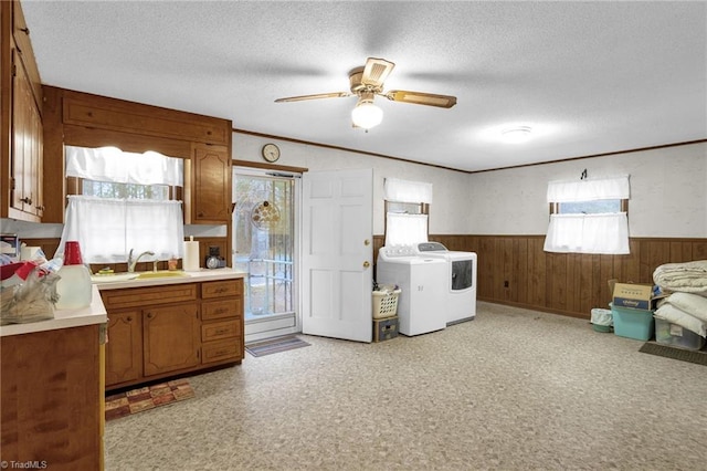 kitchen with sink, ceiling fan, washing machine and dryer, ornamental molding, and a textured ceiling