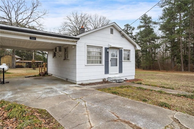 bungalow-style house with a carport and a wall mounted AC