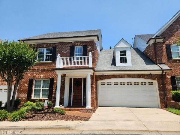 20 Waterline Dr, Greensboro, NC 27455 - georgian-style home with a balcony, a garage, driveway, and brick siding