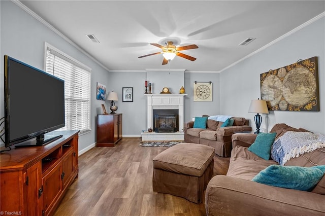 living room with ceiling fan, light wood-type flooring, and ornamental molding