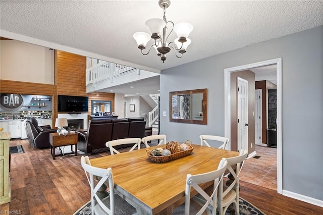 6404 Muirfield Dr, Greensboro, NC 27410 - dining room featuring a chandelier, stairway, wood finished floors, a textured ceiling, and a fireplace