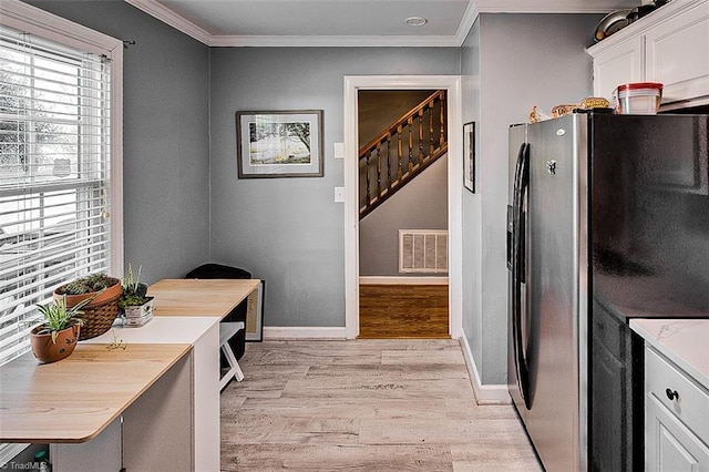 interior space featuring white cabinets, ornamental molding, and stainless steel fridge