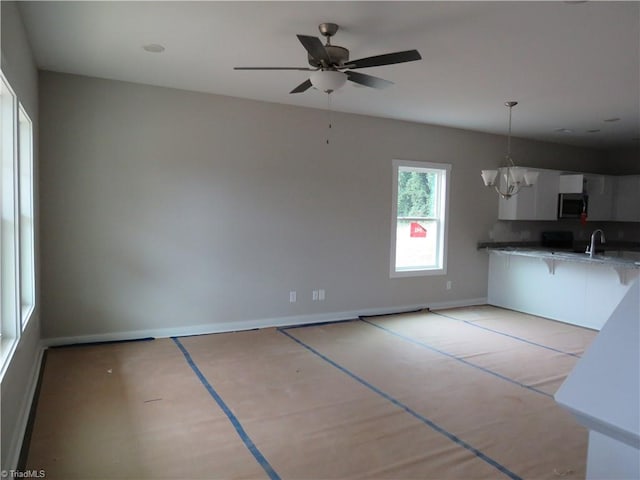 kitchen with sink, decorative light fixtures, ceiling fan with notable chandelier, and white cabinets