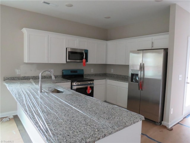 kitchen with kitchen peninsula, appliances with stainless steel finishes, sink, and white cabinets