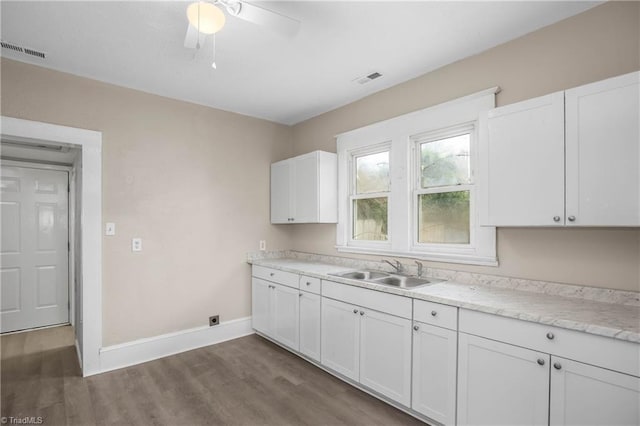 kitchen featuring visible vents, a sink, dark wood-style floors, white cabinets, and baseboards