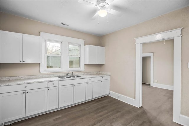 kitchen with a ceiling fan, a sink, white cabinets, light countertops, and baseboards