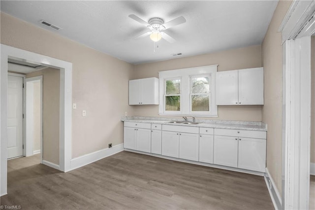 kitchen featuring visible vents, ceiling fan, light countertops, white cabinetry, and a sink