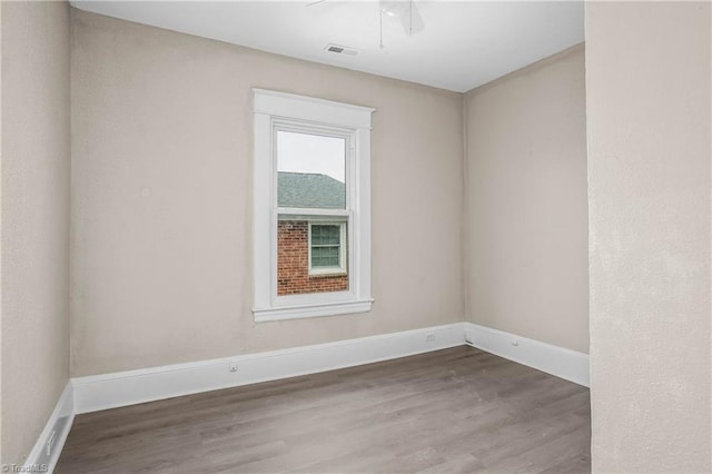 spare room featuring visible vents, baseboards, ceiling fan, and wood finished floors