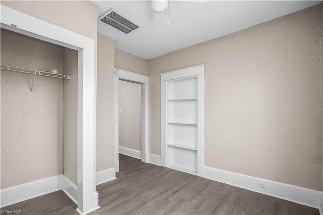 unfurnished bedroom with wood finished floors, visible vents, a closet, and baseboards