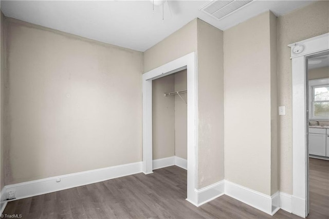 unfurnished bedroom featuring a sink, visible vents, baseboards, and wood finished floors