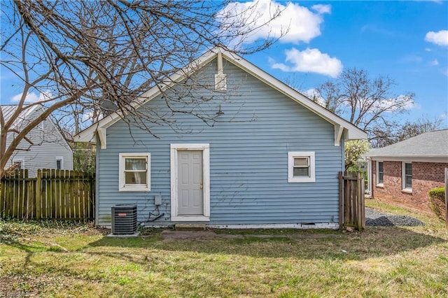 rear view of property with a lawn, central AC, and fence