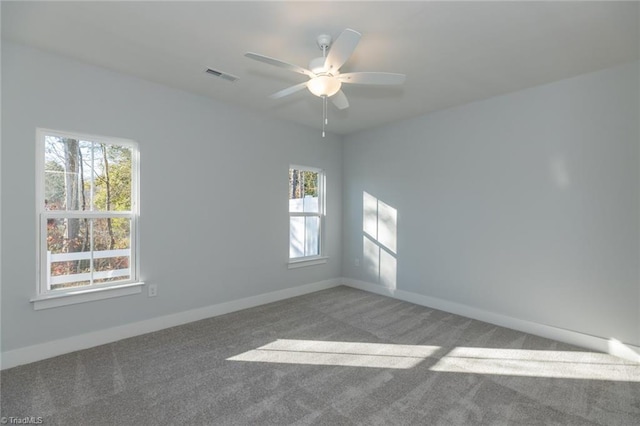 carpeted spare room featuring baseboards, visible vents, and a ceiling fan