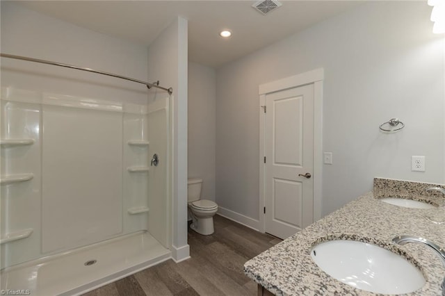 full bath featuring toilet, wood finished floors, a sink, and visible vents