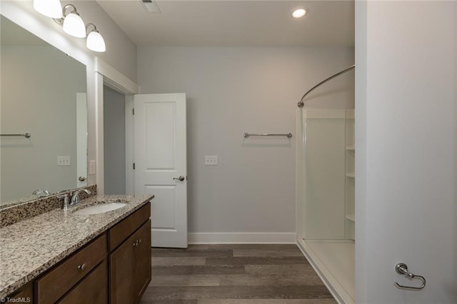 bathroom featuring recessed lighting, vanity, wood finished floors, baseboards, and walk in shower