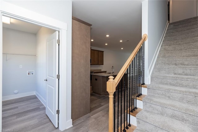 staircase with wood-type flooring and sink