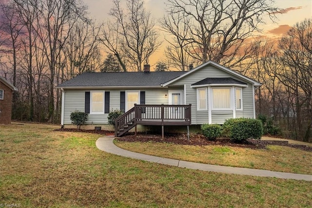 view of front of property with a wooden deck and a lawn