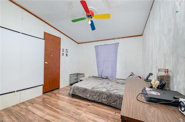 bedroom with light wood-type flooring, vaulted ceiling, crown molding, and ceiling fan