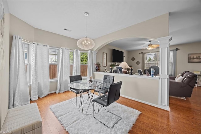 dining room with decorative columns, arched walkways, wood finished floors, baseboards, and ceiling fan
