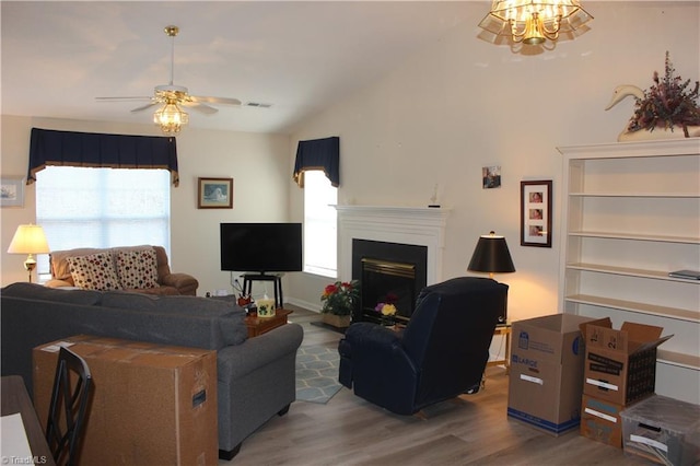 living room with a wealth of natural light, a fireplace, vaulted ceiling, and wood finished floors