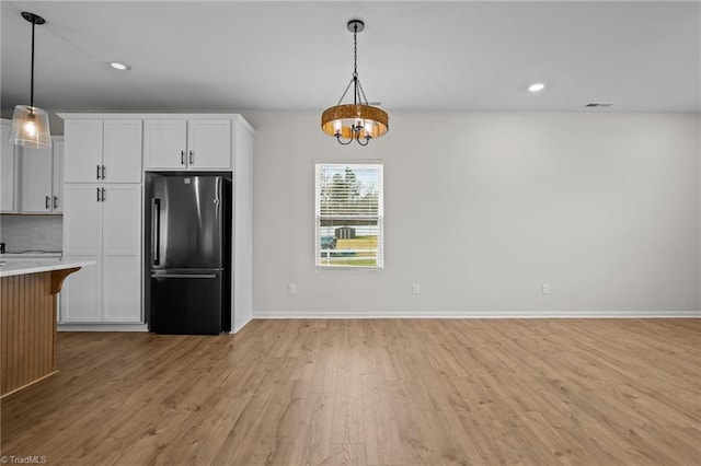 kitchen featuring white cabinets, stainless steel fridge, and hanging light fixtures