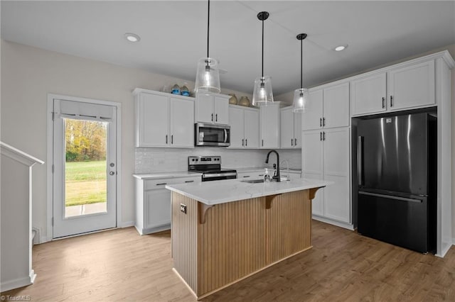 kitchen with a center island with sink, sink, appliances with stainless steel finishes, light hardwood / wood-style floors, and white cabinetry