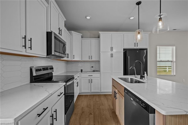 kitchen featuring sink, stainless steel appliances, pendant lighting, a kitchen island with sink, and white cabinets