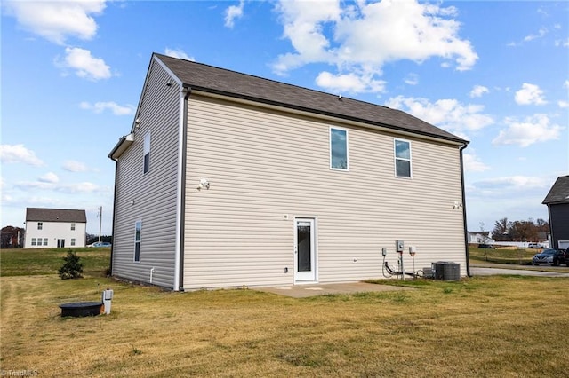 rear view of house with central air condition unit, a patio area, and a lawn