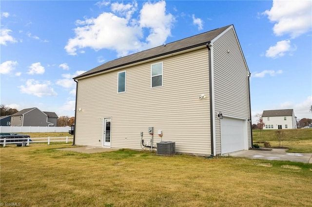 back of house featuring a yard, a garage, and cooling unit