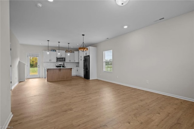 kitchen featuring hanging light fixtures, a kitchen island, appliances with stainless steel finishes, light hardwood / wood-style floors, and white cabinetry