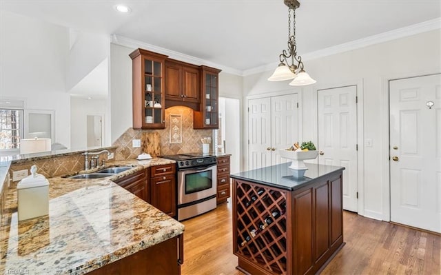 kitchen with sink, kitchen peninsula, crown molding, pendant lighting, and stainless steel stove