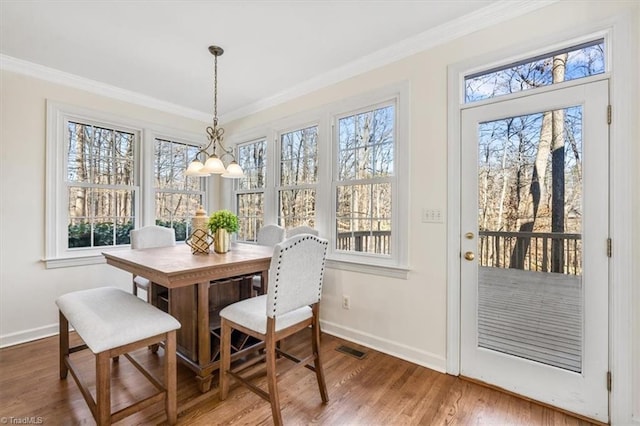 dining space featuring hardwood / wood-style floors, an inviting chandelier, a wealth of natural light, and crown molding