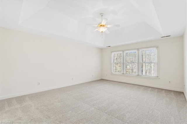 unfurnished room featuring carpet, ceiling fan, and a raised ceiling