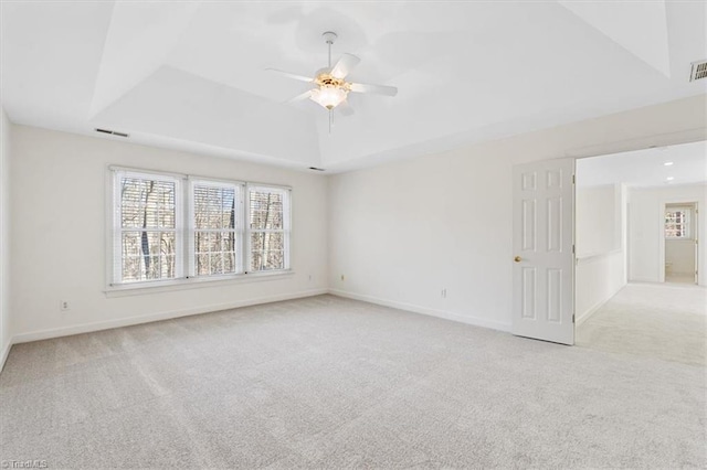 carpeted empty room with ceiling fan and a tray ceiling