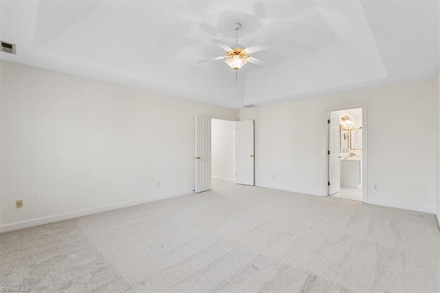 carpeted empty room with a raised ceiling and ceiling fan